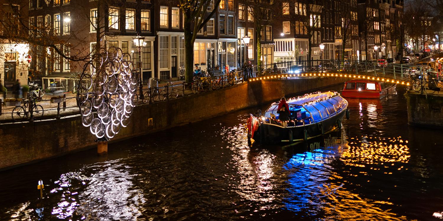Vrienden aan boord van een Amsterdamse grachtenboot tijdens het lichtfestival
